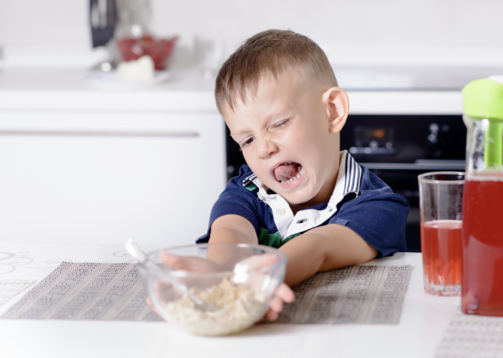 A young autistic child refusing food at the dinner table